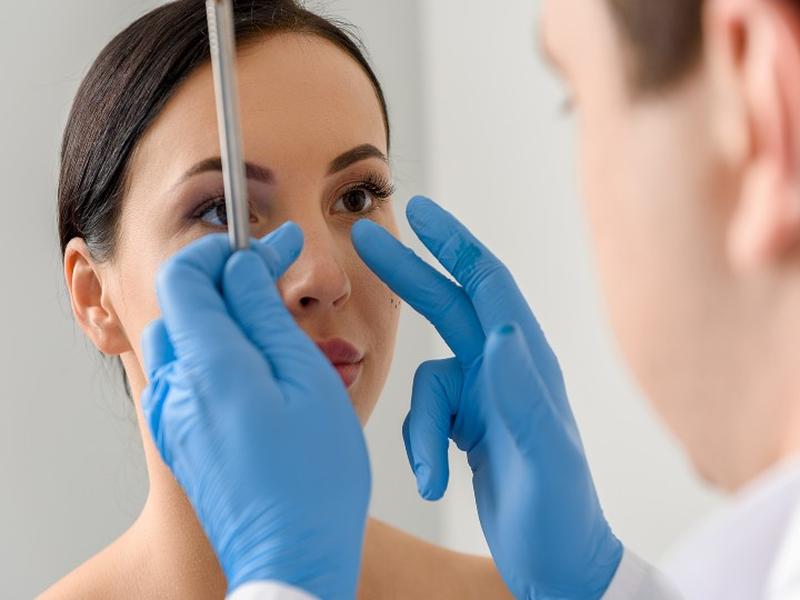 Médico revisa nariz de mujer previo a cirugía