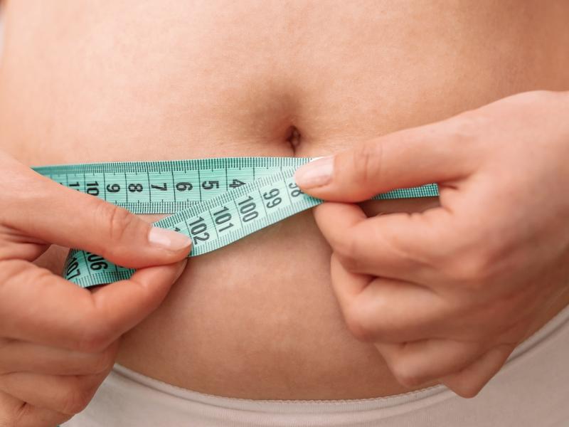 Una mujer mide su abdomen. 