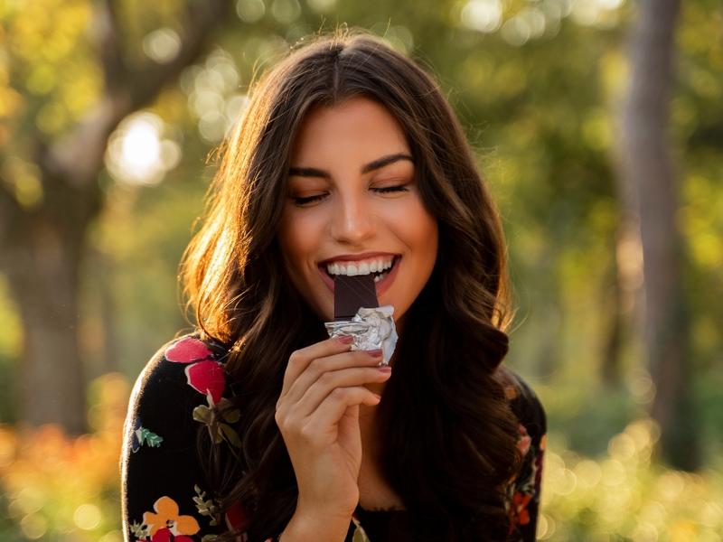 Una mujer disfruta comiendo una barra de chocolate. 