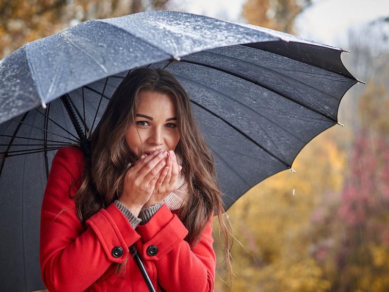 Chica con paraguas negro con frío / Foto: iStock