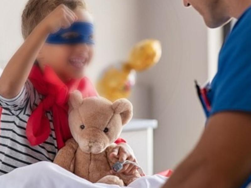 Niño en cama de hospital vestido de super héroe