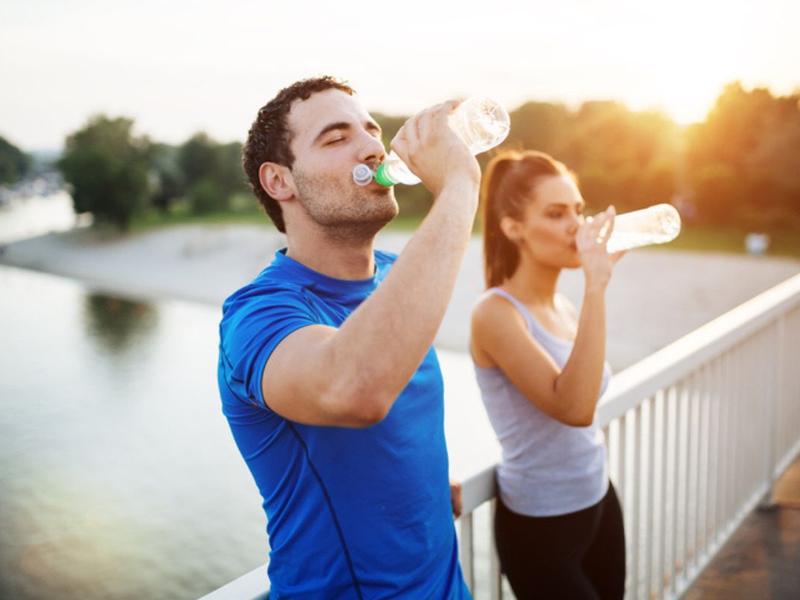 Hombre y mujer tomando agua para explicar la hidratación en temporada de calor
