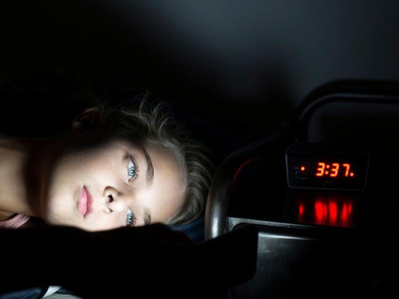 Joven adolescente viendo el celular en la madrugada para ilustrar los síntomas de insomnio en adolescentes