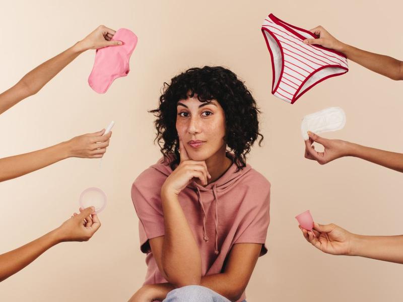Mujer piensa mientras le ofrecen diferentes métodos para la menstruación. 