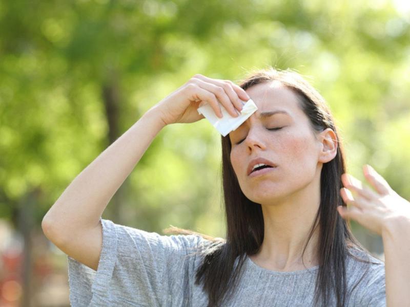 Mujer con calor se pregunta por los riesgos de la deshidratación 