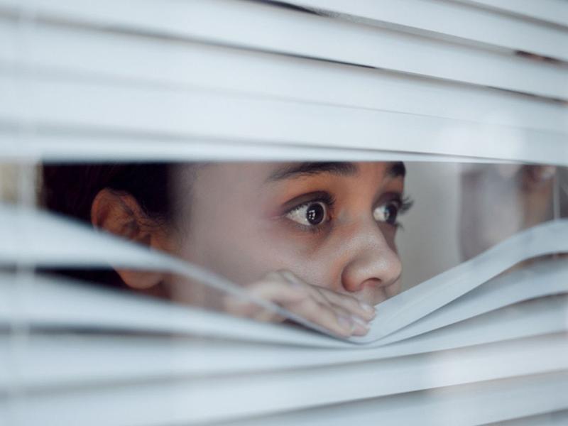 Mujer mirando por la ventana con miedo se pregunta por qué surgen las fobias