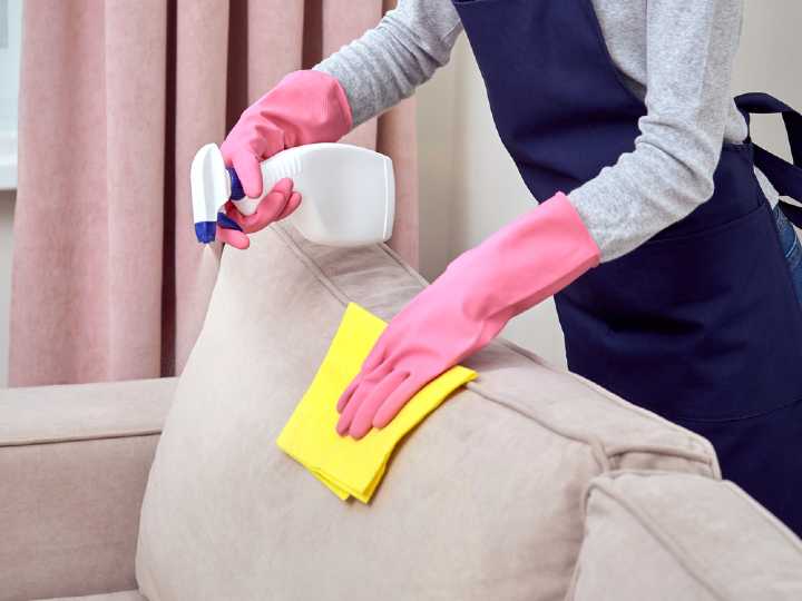 Mujer limpiando el sillón con limpiador natural para eliminar suciedad