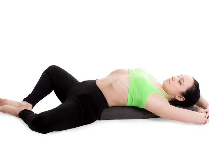 Mujer haciendo postura de diosa reclinada de yoga para la endometriosis