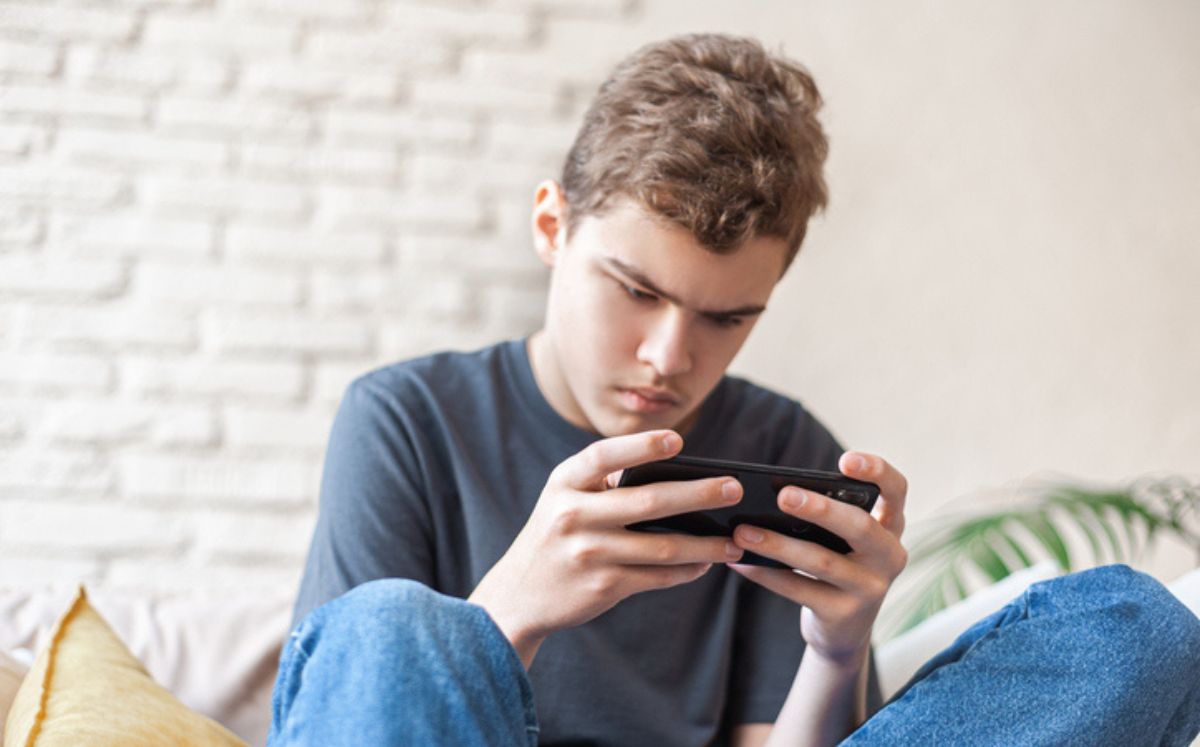 Joven con celular busca los 6 mitos sobre el autismo