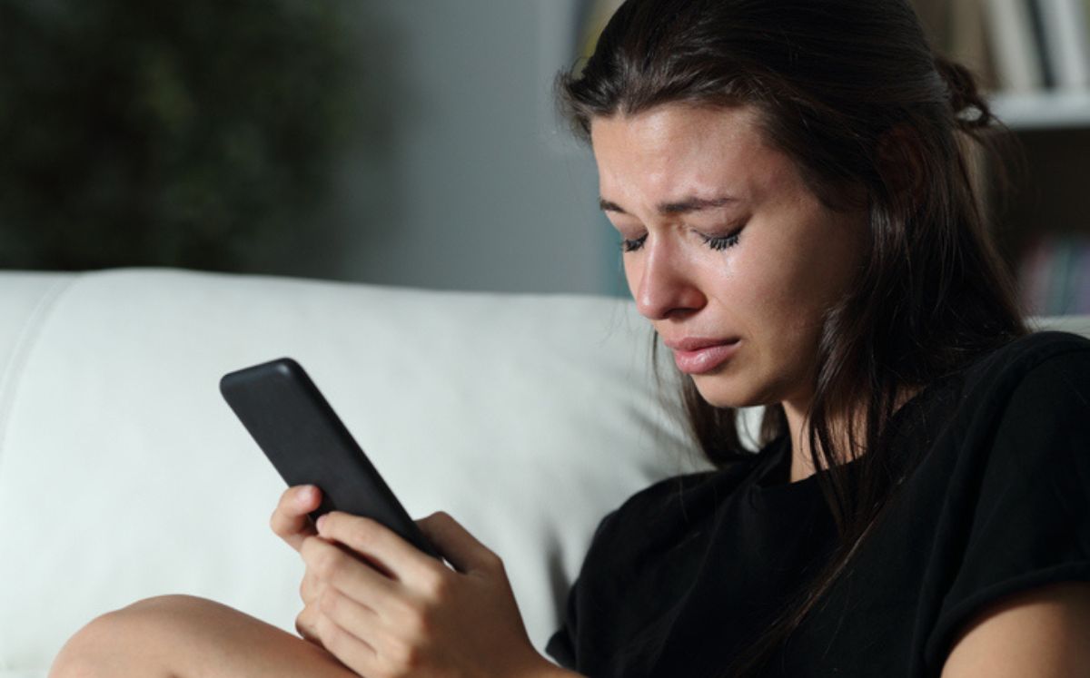 Mujer llorando mira su teléfono para buscar los beneficios del llanto