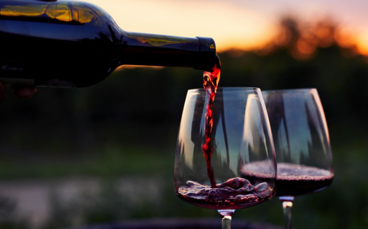 Botella sirviendo vino tinto para explicar sus beneficios