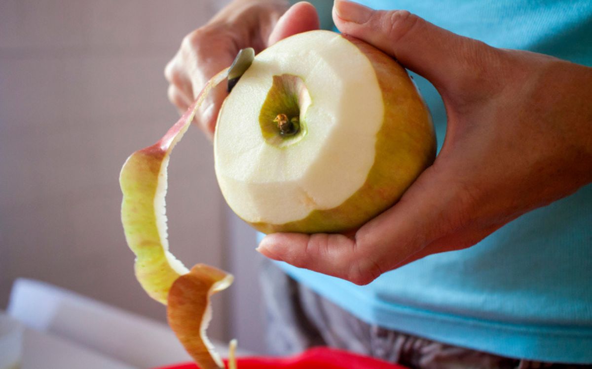 Persona pelando manzana sin saber si ¿Comer fruta con cáscara o sin cáscara?, te decimos cómo aprovecharlas al máximo