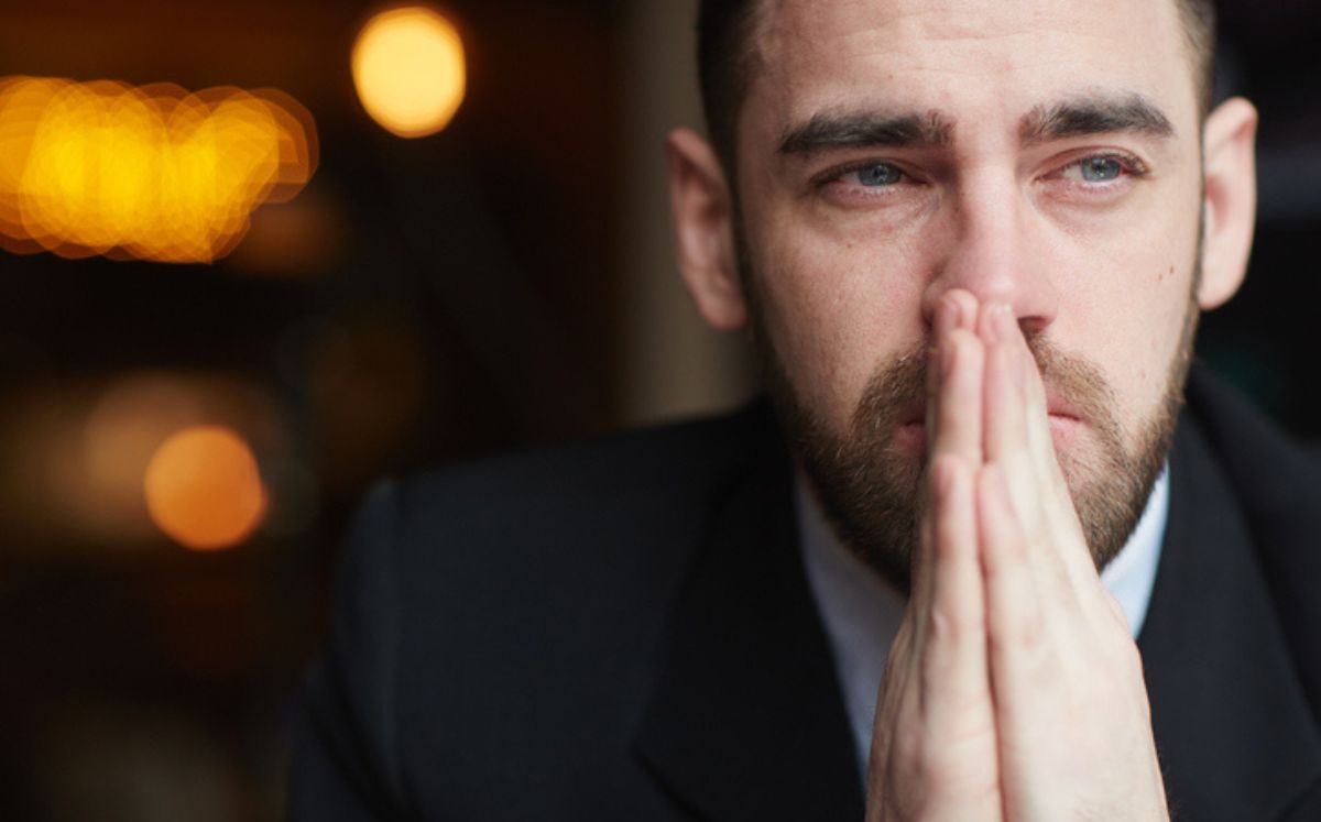 Hombre con manos en la cara llora para explicar los beneficios del llanto