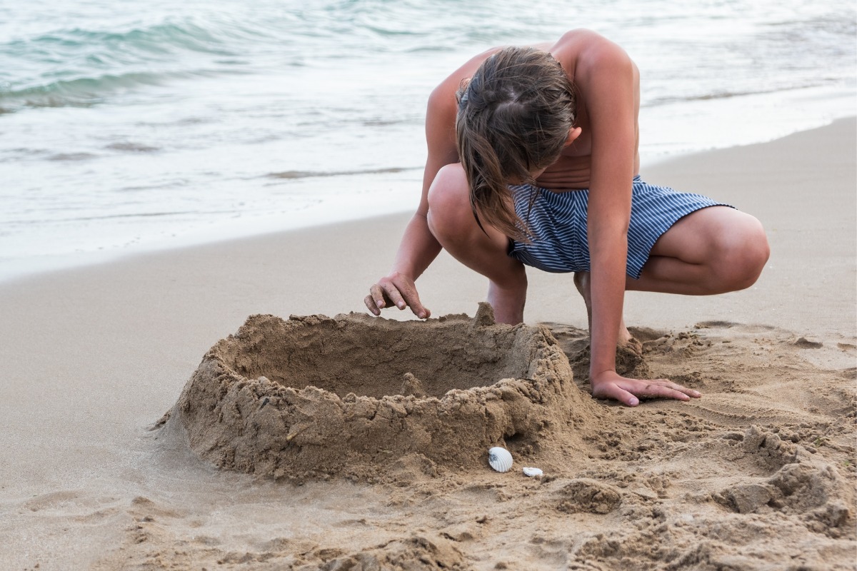 Joven no conoce los peligros de la arena de la playa para él y su familia. 