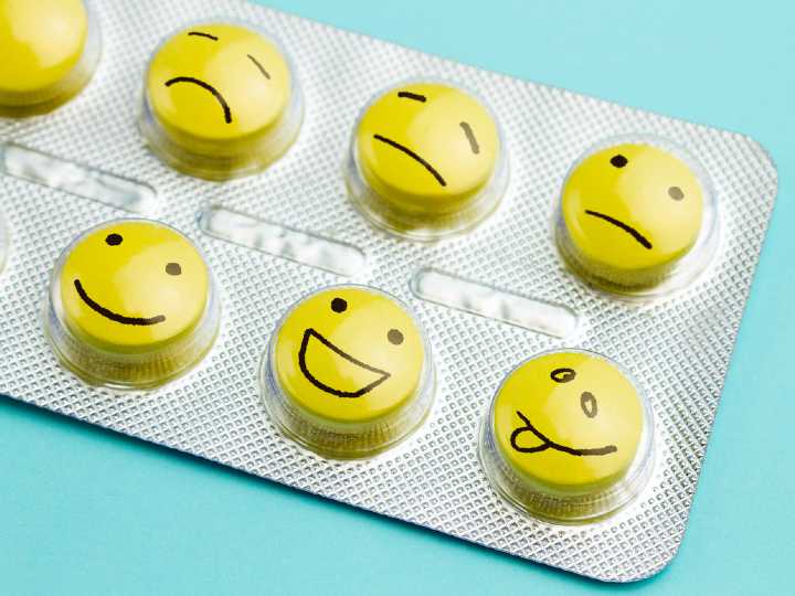 Pastillas amarillas con caras de tristes a sonrientes como concepto de antidepresivos que sanan