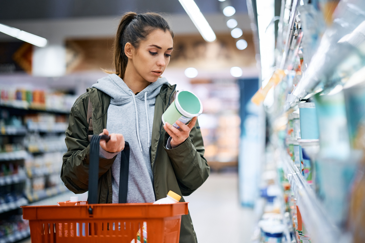 Mujer revisa etiqueta de alimentos en supermercado
