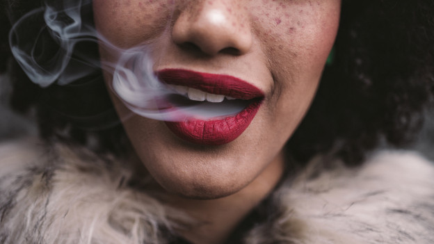 Mujer sacando humo de la boca por cigarro