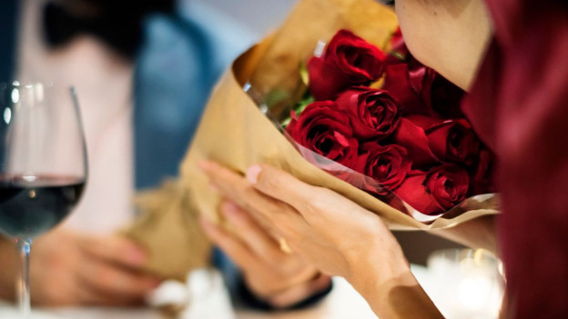 Mujer recibe ramo de rosas en cena