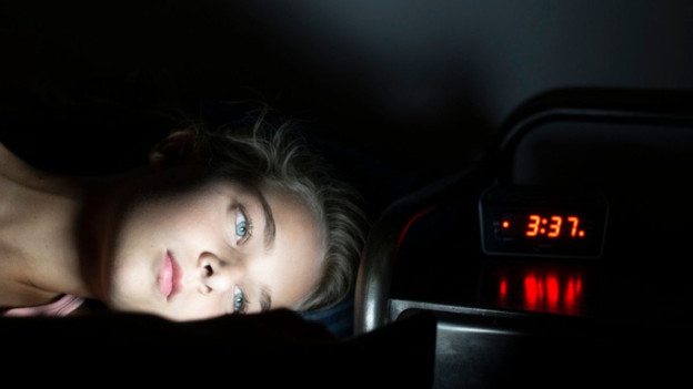 Joven adolescente viendo el celular en la madrugada para ilustrar los síntomas de insomnio en adolescentes