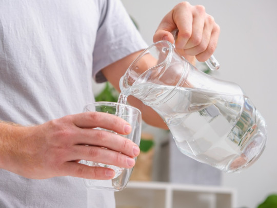 Hombre toma agua sin saber los 5 mitos del consumo de agua. 