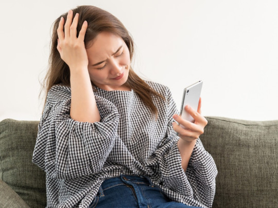 Mujer con dolor no sabe cómo el uso del celular afecta a tu cerebro. 