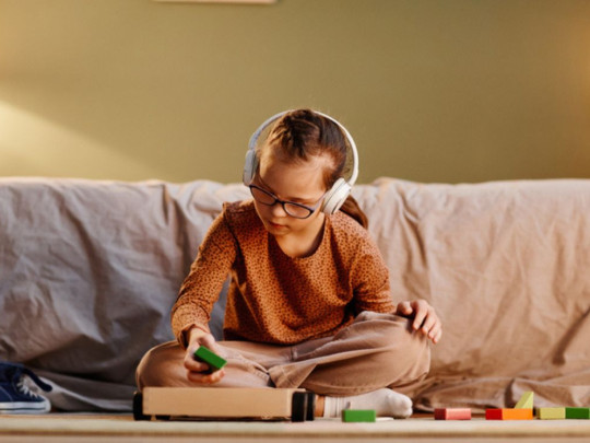 Niña con audífonos juega para entender los tipos de autismo 