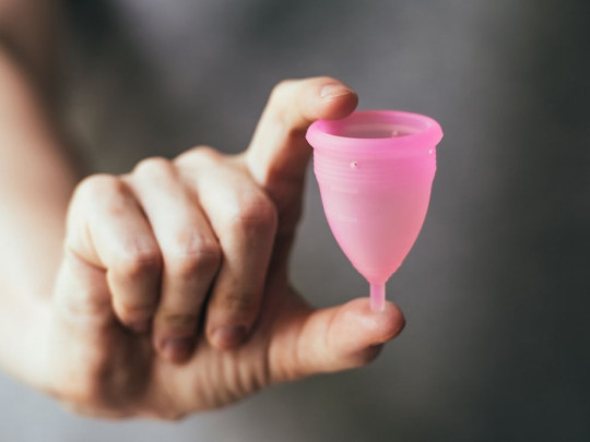 Persona sosteniendo copa menstrual que puede quitar cólicos