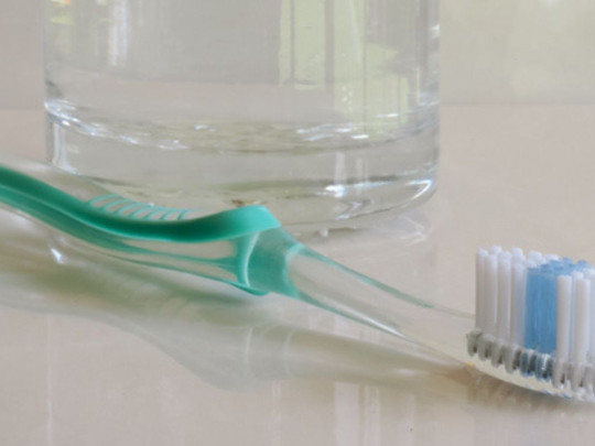 Vaso con agua junto a cepillo de dientes para ilustrar ¿Cómo desinfectar el cepillo de dientes con agua oxigenada?
