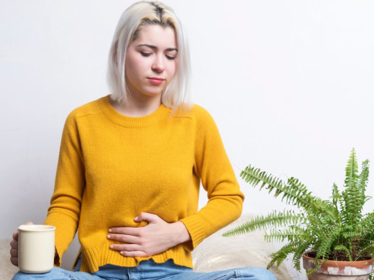 Mujer con mano en el abdomen se pregunta sobre los Probióticos y simbióticos, ¿cuál mejora la digestión y quita la inflamación más rápido?
