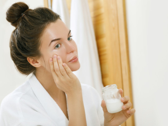 Mujer se aplica crema de ácido hialurónico en el rostro
