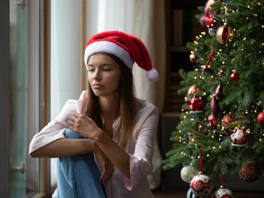 Mujer triste junto a árbol de Navidad