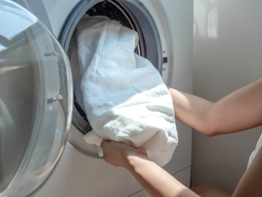 Mujer lava ropa blanca en lavadora