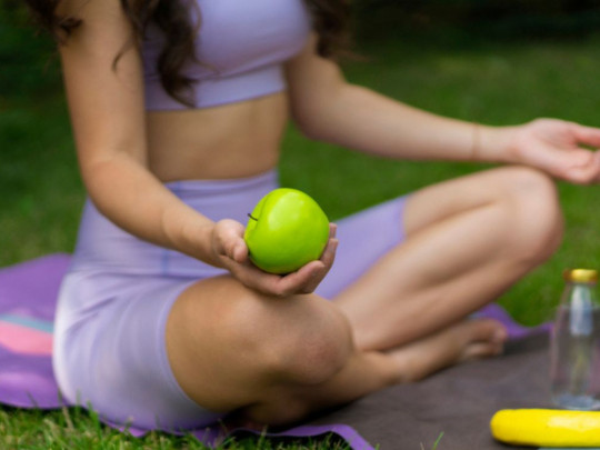 Mujer meditando sostiene una manzana para ilustrar cuántas calorías tiene una manzana