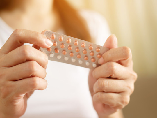 Mujer con pastillas anticonceptivas en la mano