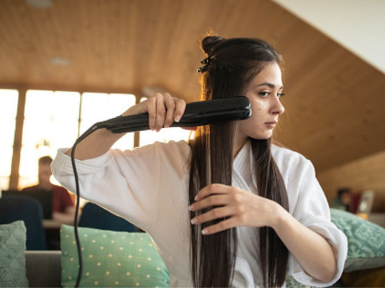 Mujer alaciándose el cabello para mostrar si los productos para alaciar el cabello dañan los riñones