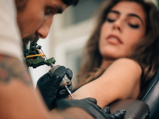 Hombre tatuando brazo de mujer