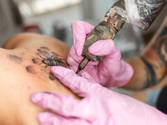 Mujer tatuando brazo