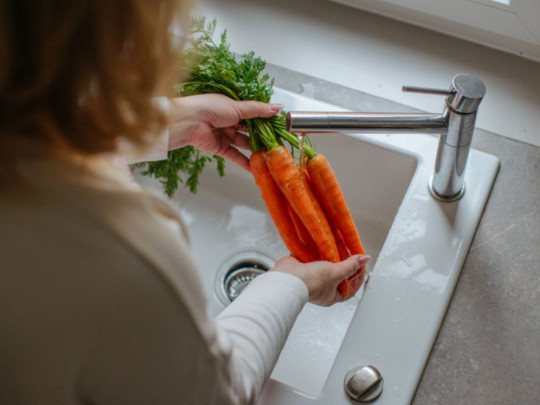 Mujer lavando zanahorias porque sabe para qué sirve y que previene el cáncer de mama