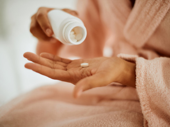 Mujer en bata de baño con paracetamol en mano