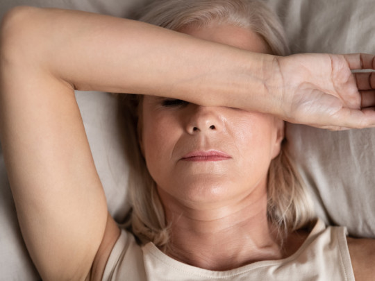 Mujer con malestar acostada se pregunta cuáles son las diferencias entre perimenopausia y menopausia