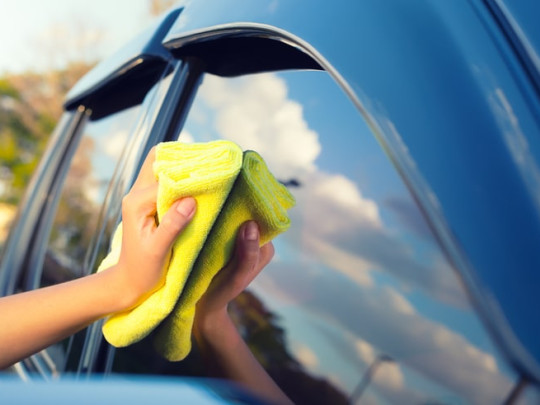 Mujer limpia los vidrios del automóvil con papa