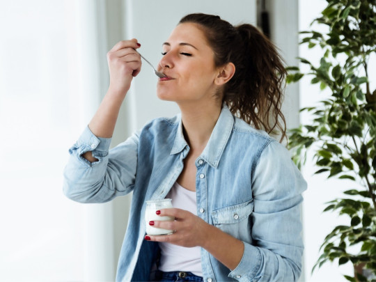 Mujer disfruta del postre de yogurt con limón para bajar de peso en su casa.