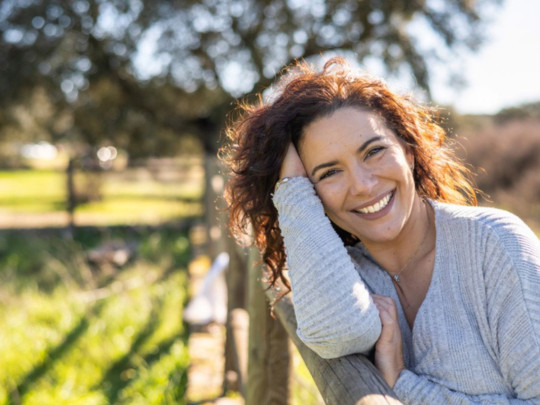 Mujer sonriendo al aire libre para explicar los beneficios de la primavera