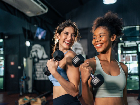 Mujeres sonríen y hacen ejercicio mientras su salud corre riesgo en el gym