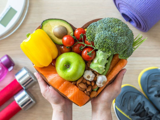 Plato de corazón con verduras y frutas que se incluyen en la dieta para bajar el colesterol
