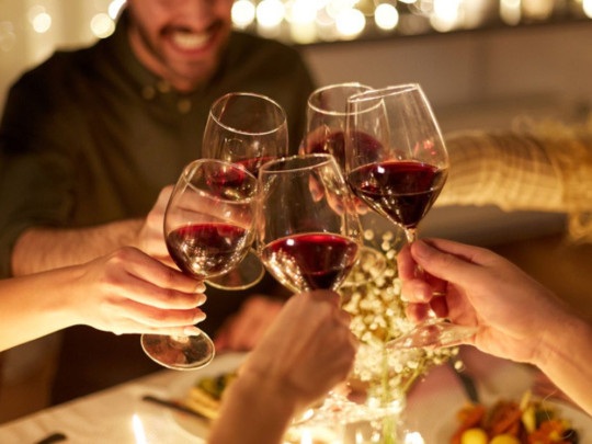 Personas brindando con copas por los beneficios del vino tinto