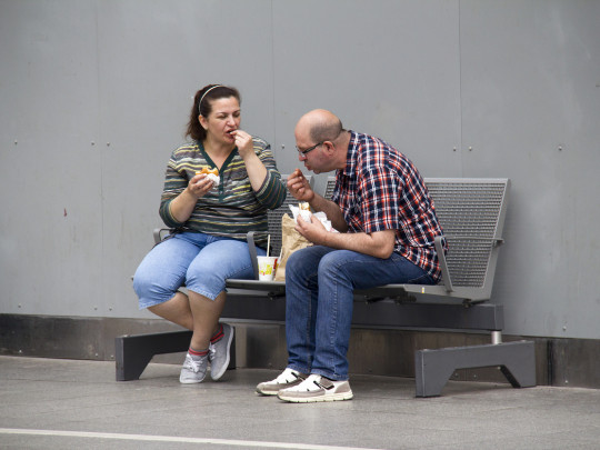 Personas sentadas en banca del metro para explicar las enfermedades por comer en el metro