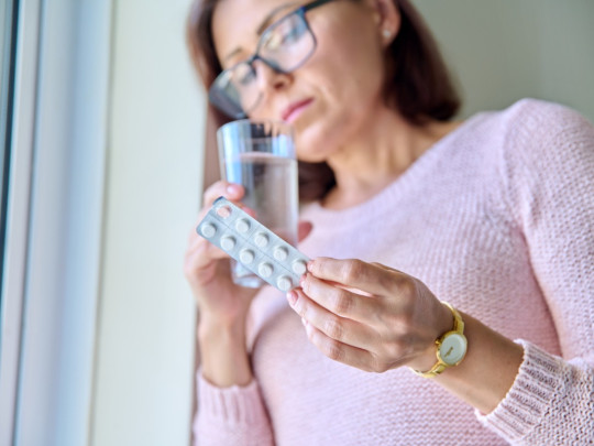 Mujer toma vitaminas para no tener problemas con la menopausia. 