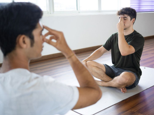 Hombre enseñando a respirar a otro para ilustrar qué es yoga