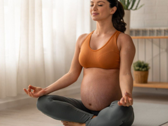 Mujer embarazada meditando para mostrar cómo hacer yoga para recibir a tu bebé